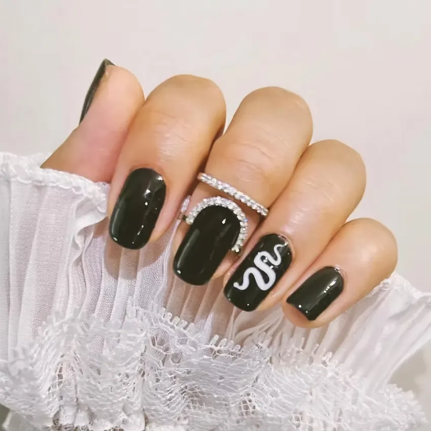 beautiful manicured nails painted black with a snake painted on one finger